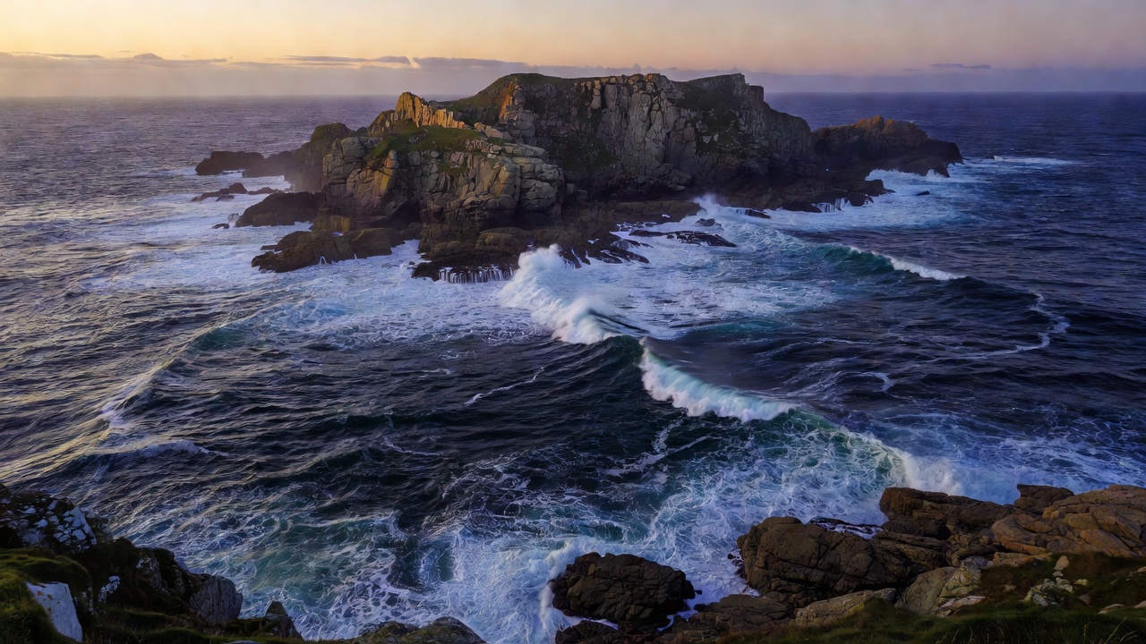 Cornish headland at dusk with lines of swell wrapping around the rocks